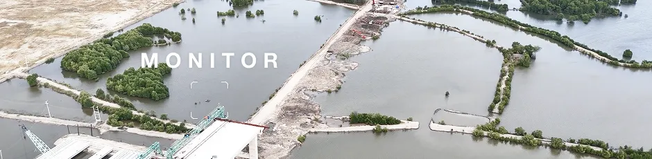 Aerial view of flooded land with patches of green vegetation and a partially constructed building near water bodies.